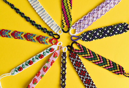 Woven DIY friendship bracelets handmade of embroidery bright thread with knots isolated on yellow background.の写真素材