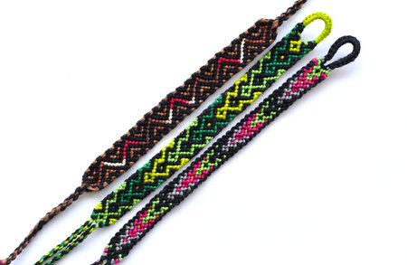 Woven DIY friendship bracelets handmade of embroidery bright thread with knots on white background.