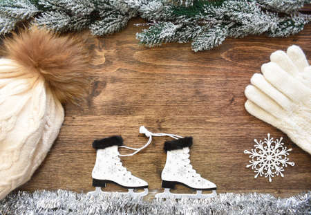 Wooden Christmas tree toy Skates with snowflakes, tied with rope, on white tinsel imitating ice. Snowy 
fir branches from above. Wooden background with copy space. Creative New Year composition.の写真素材