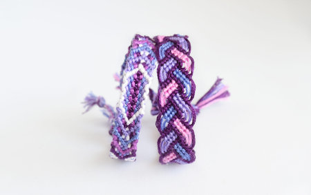 Woven DIY friendship bracelet handmade of embroidery bright thread with knots isolated on white...