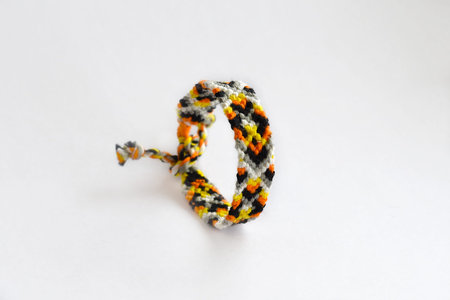 Tied woven friendship bracelets with bright colorful patterns handmade of thread isolated on white...