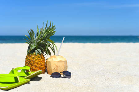 Pineapple with sunglasses, flip-flops and coconut drink on white sand beach in Vietnamの写真素材