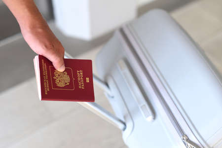 A hand holding Russian passport and suitcaseの写真素材