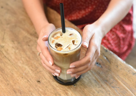 Woman's hands  holding a glass of ice coffeeの写真素材