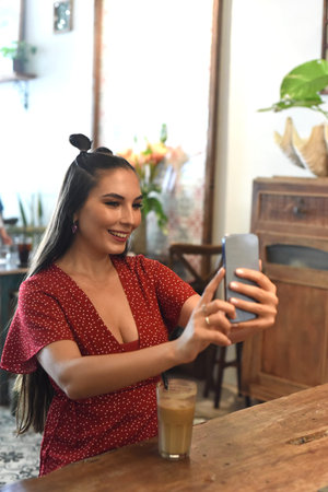 Young woman taking selfie in a coffee shop
