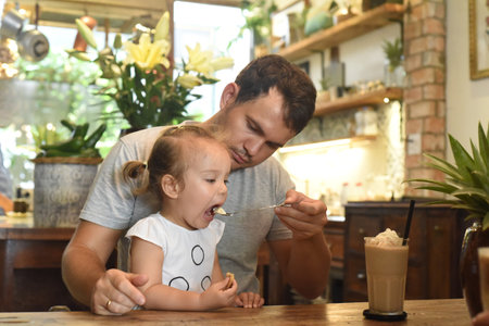 Father and daughter eating cream from frappe in a cafeの写真素材