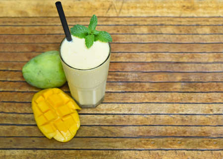 Mango lassi with sliced fresh mango on wooden backgroundの写真素材