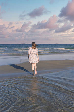 Beautiful Belarus woman walking on the beach against dramatic and romantic skyの写真素材