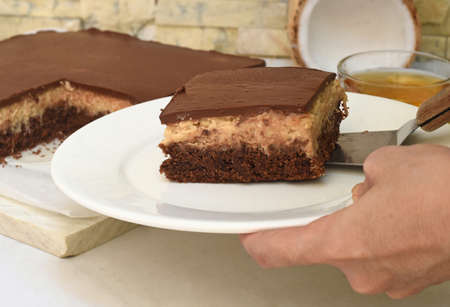 Hand serving piece of Bounty Cake on a plateの写真素材