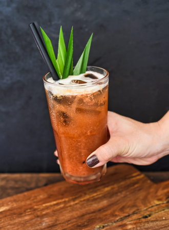Hand holding iced tropical tea made of green tea and orange jam on wooden table backgroundの写真素材