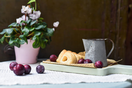 whipped cream tubes with cup and plums on wooven cloth on black backgroundの写真素材