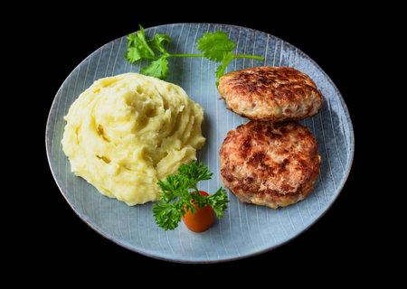 mashed potatoes with meat cutlets on a black background side viewの写真素材