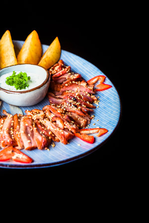 Goose fillet fried with garlic served with potato wedges and kim chi on black background top viewの写真素材