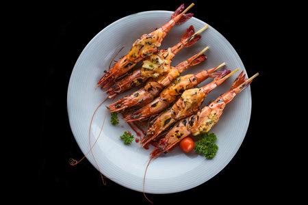 Six grilled shrimps with cheese on blue plate isolated on black background top viewの写真素材