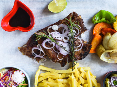 Grilled smoked pork ribs with french fries and soy sauce and salad on wooden boardの写真素材