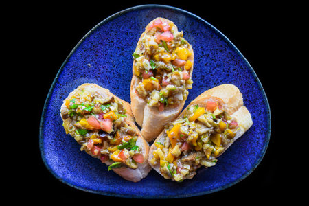 Vegetarian Bruschetta with tomatoes, eggplant, pepper and olive oil on blue plate close upの写真素材