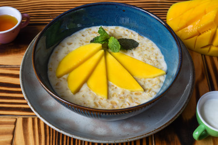 Oatmeal served with mango on a wooden table close upの写真素材