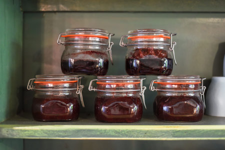 Jars with homemade jam on a wooden shelf in a rowの写真素材