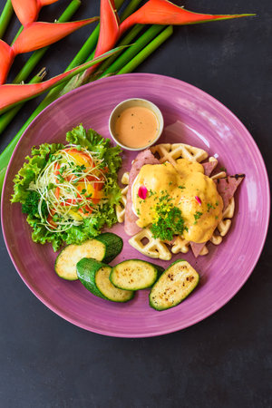 Eggs Benedict (poached eggs) on grilled ham with holland sauce on belgian waffles with grilled zucchiniの写真素材