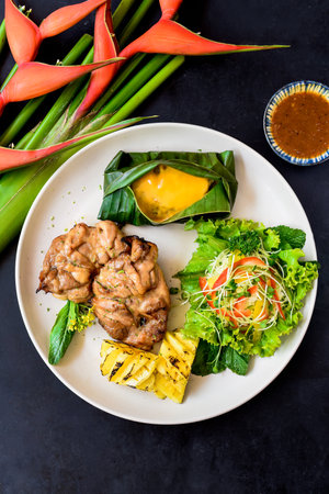 Vietnamese chicken boneless legs with baby corn under cheese, salad and grilled pineappleの写真素材