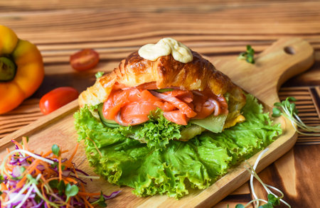 croissant wish smoked salmon fillet and vegetables on wooden table close up side viewの写真素材