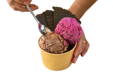 Hand with spoon holding piece of  homemade ice crem Tiramisu and Hibiscus isolated on white...