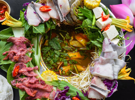 Vietnamese hot pot with raw seafood on black background