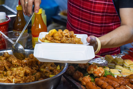Vietnamese woman serving chicken paws in plastic box with chili in vietnamese night marketの写真素材
