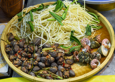 Vietnamese stewed seashells in sauce in the night market on food festival