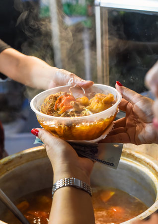 Vietnamese woman serving noodles soup with meat in vietnamese night market in food festivalm person buyingの写真素材