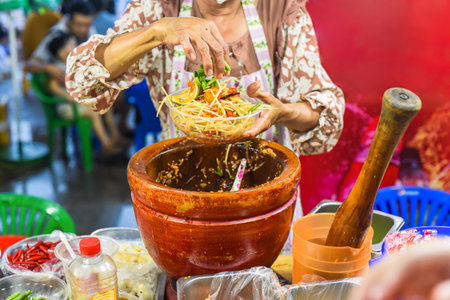 Vietnamese woman serving noodles with vegetables in vietnamese night market in food festivalの写真素材