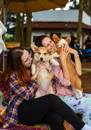 mother with her daughter hugging their corgi dogs in the gardenの写真素材