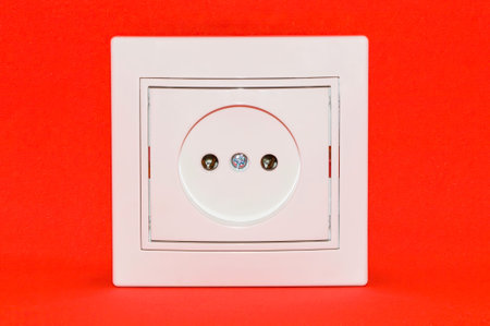 White electric socket isolated on red background