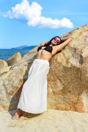 Young ukrainian woman in bikini and long skirt laying on the stoneの写真素材