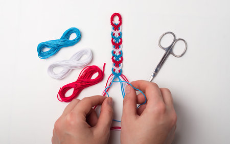 Process of weaving knot for DIY friendship bracelet. Female hands. step by step. White background...