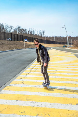 Young man riding a skateboard on a pedestrian cross road