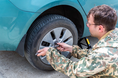young man changing a car tire for winter tiresの写真素材