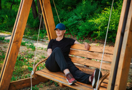 Young russian woman it sport outwear resting on swing after making exercisesの写真素材