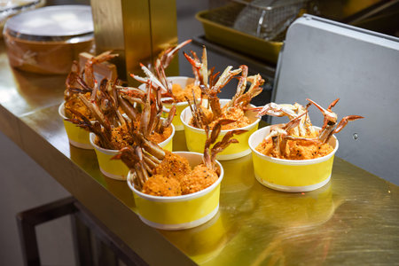 Crispy fried crab claws served in yellow paper bowls at a Shanghai street food stall. Crunchy texture and golden coating ready to eatの写真素材