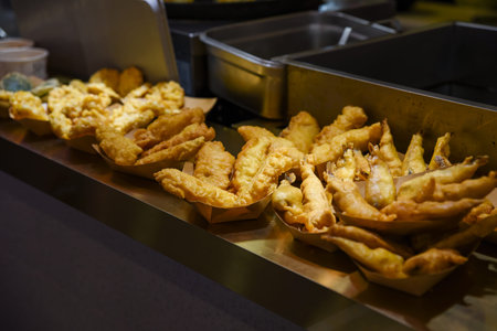 Golden battered fish fillets displayed in paper trays at a Chinese street food stall. Hot, crunchy...