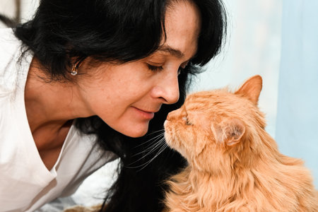 50 year old russian woman with her 20 year old ginger cat close upの写真素材