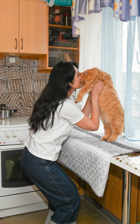 happy brunette woman holding and hugging her senior cat at homeの写真素材