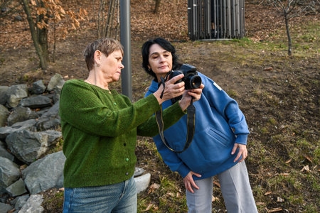 Two Russian women in their 50 years old and 60 years old enjoy photography outdoors, showing active aging, mindfulness, friendship and the joy of pursuing a creative hobby.の写真素材