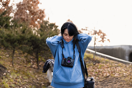 Russian woman 50 years old prepares for her hobby as a photographer enjoying a calm moment before shooting embracing creativity and the pleasant flow of inspirationの写真素材
