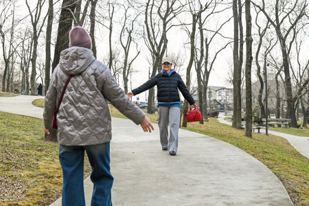 Two women walk toward each other with open arms in a spring park, showing anticipation, warmth, mindfulness and emotional connection.の写真素材