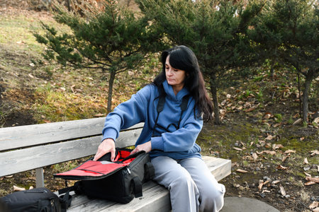 Russian woman 50 years old organizes gear in a camera backpack, showing calm focus and mindful care for equipment and the importance of protecting tools.の写真素材