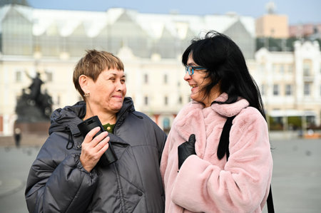 Two Russian friends, 50 and 60 years old, laughing together and looking at each other with affection, showing warmth, trust, mindfulness, and genuine connection.の写真素材