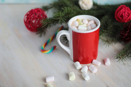 hot chocolate with marshmallows in a mug and christmas tree branch on wooden surfaceの写真素材