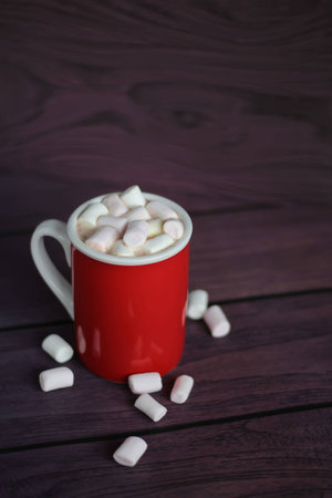 Hot cocoa in red mug with marshmallows on wooden tableの写真素材