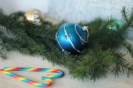 festive decorative blue bauble on christmas tree branch and candy canesの写真素材